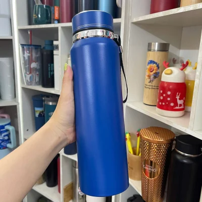 Ảnh thật nguồn bình xanh trơn nắp viền đôi được cầm trước kệ, thấy cổ sáng và quai dây