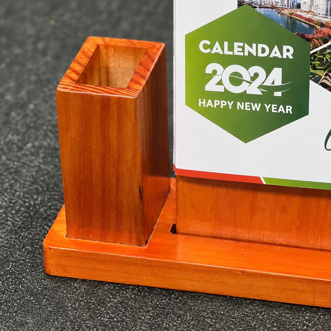 Ảnh chỉnh phóng cận ống bút miệng vuông, tông nâu cam và đế chung, giữ phần CALENDAR 2024 còn trong khung hình