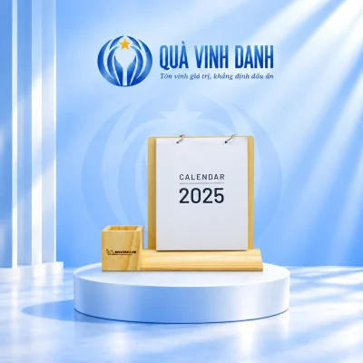 Minh họa bộ lịch đế gỗ vát trên bục Quà Vinh Danh, giữ ống bút Michelin bên trái và bìa CALENDAR 2025 bên phải