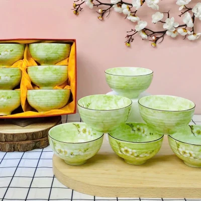 Ảnh thật sáu bát men xanh bày rời xếp ba hai một cùng một bộ sáu trong hộp phía sau giữ bối cảnh hoa và mặt gỗ