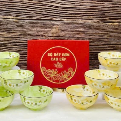 Ảnh thật so hai cấu hình mỗi bên sáu bát men xanh bên trái vàng bên phải giữ hộp đỏ chữ và hoa văn gốc