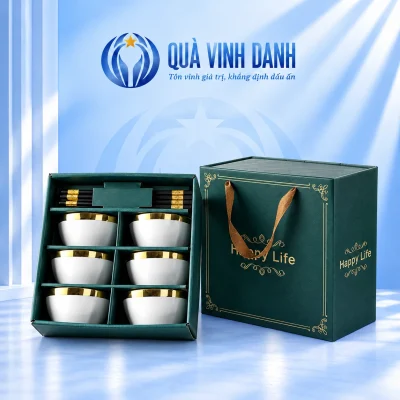 Minh họa bộ sáu bát trắng viền vàng trong hộp xanh kèm đũa và tư liệu hộp Happy Life trên nền Quà Vinh Danh không bục