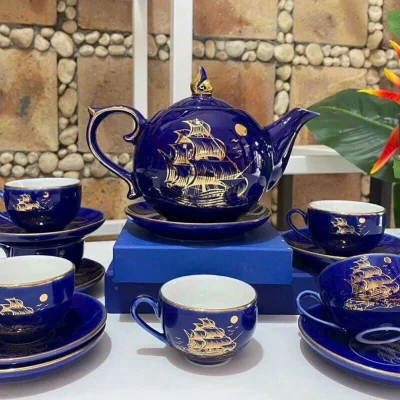 Ảnh chụp nguồn bộ trà xanh đậm có thuyền buồm, mặt trăng, chén đặt nghiêng và đĩa xếp chồng, giữ nguyên họa tiết