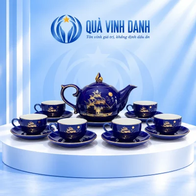 Bộ trà Bưởi Lửa số 2 xanh đậm giữ thuyền buồm, mặt trăng, một ấm và sáu chén có quai trên bục Quà Vinh Danh