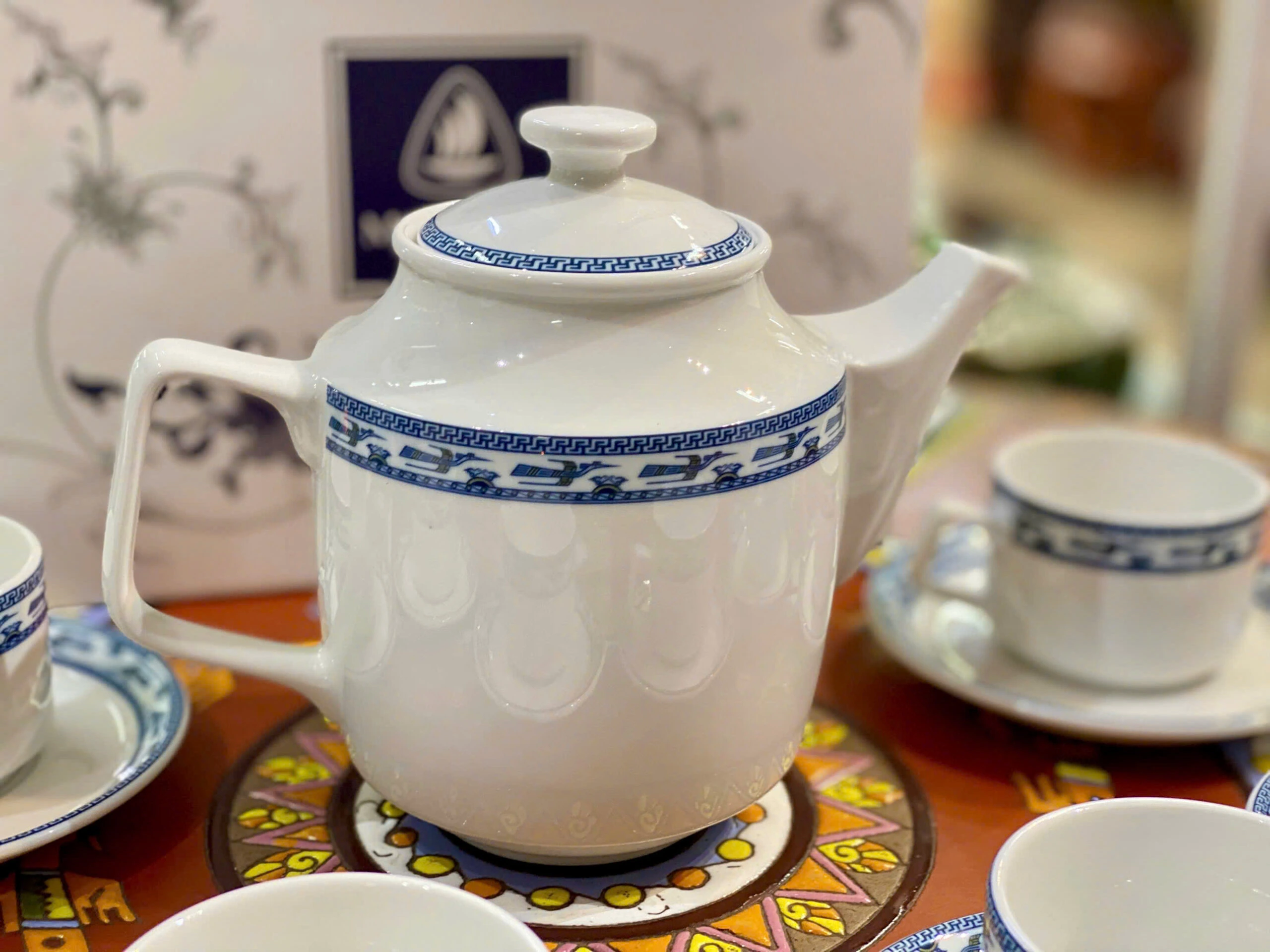 Ảnh chụp nguồn cận ấm Jasmine Chim Lạc, quai vuông bên trái, vòi thẳng bên phải, nắp thấp và dải chim xanh