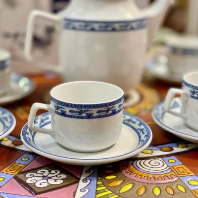 Ảnh chụp nguồn cận chén Jasmine Chim Lạc có quai góc cạnh và đĩa với dải chim xanh, giữ toàn khung gốc