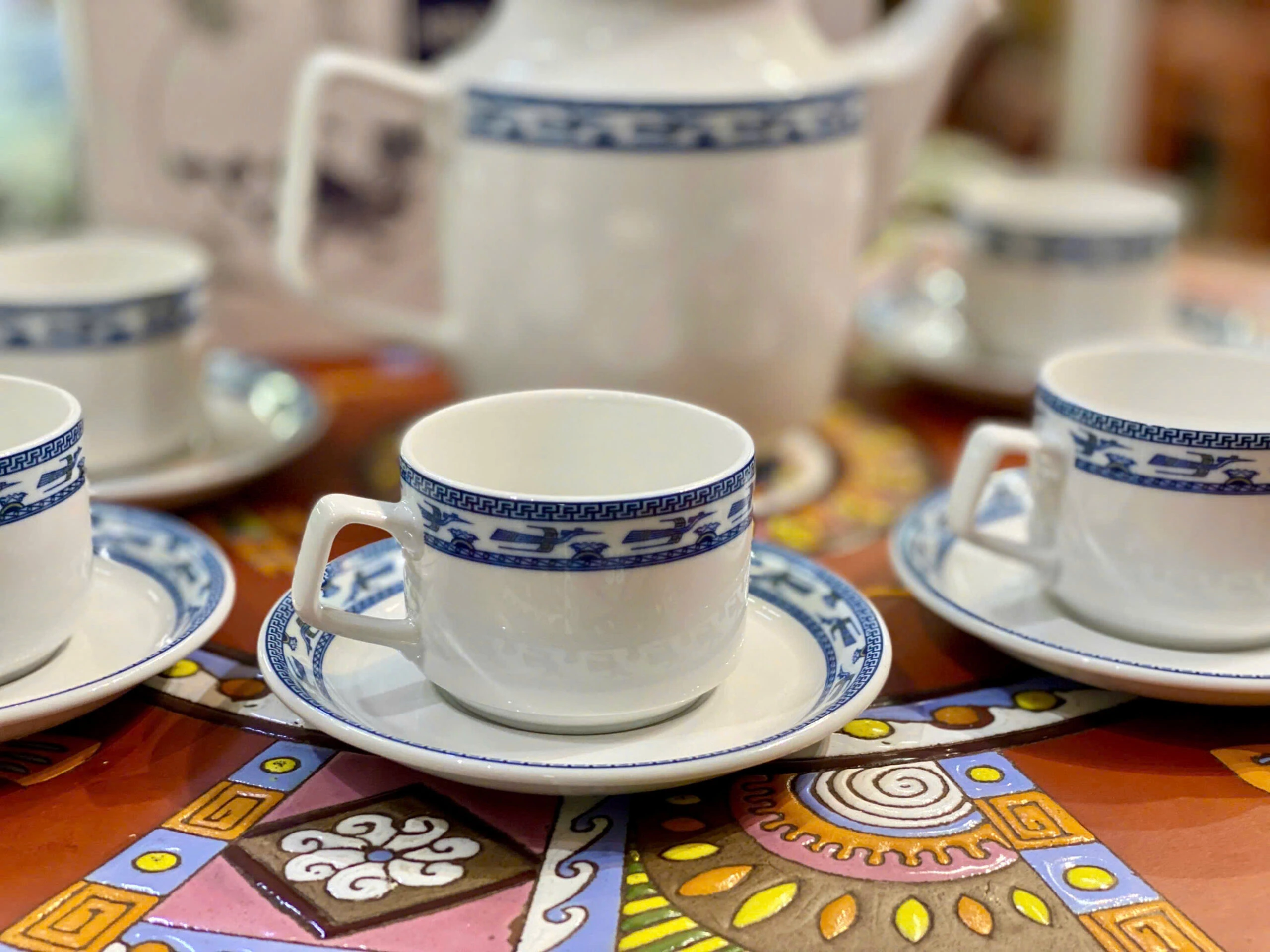 Ảnh chụp nguồn cận chén Jasmine Chim Lạc có quai góc cạnh và đĩa với dải chim xanh, giữ toàn khung gốc
