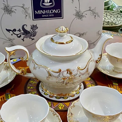 Ảnh nguồn cận ấm Đài Các với quai uốn bên trái, vòi cong bên phải, núm nắp hình hoa và chân đế, giữ họa tiết màu vàng