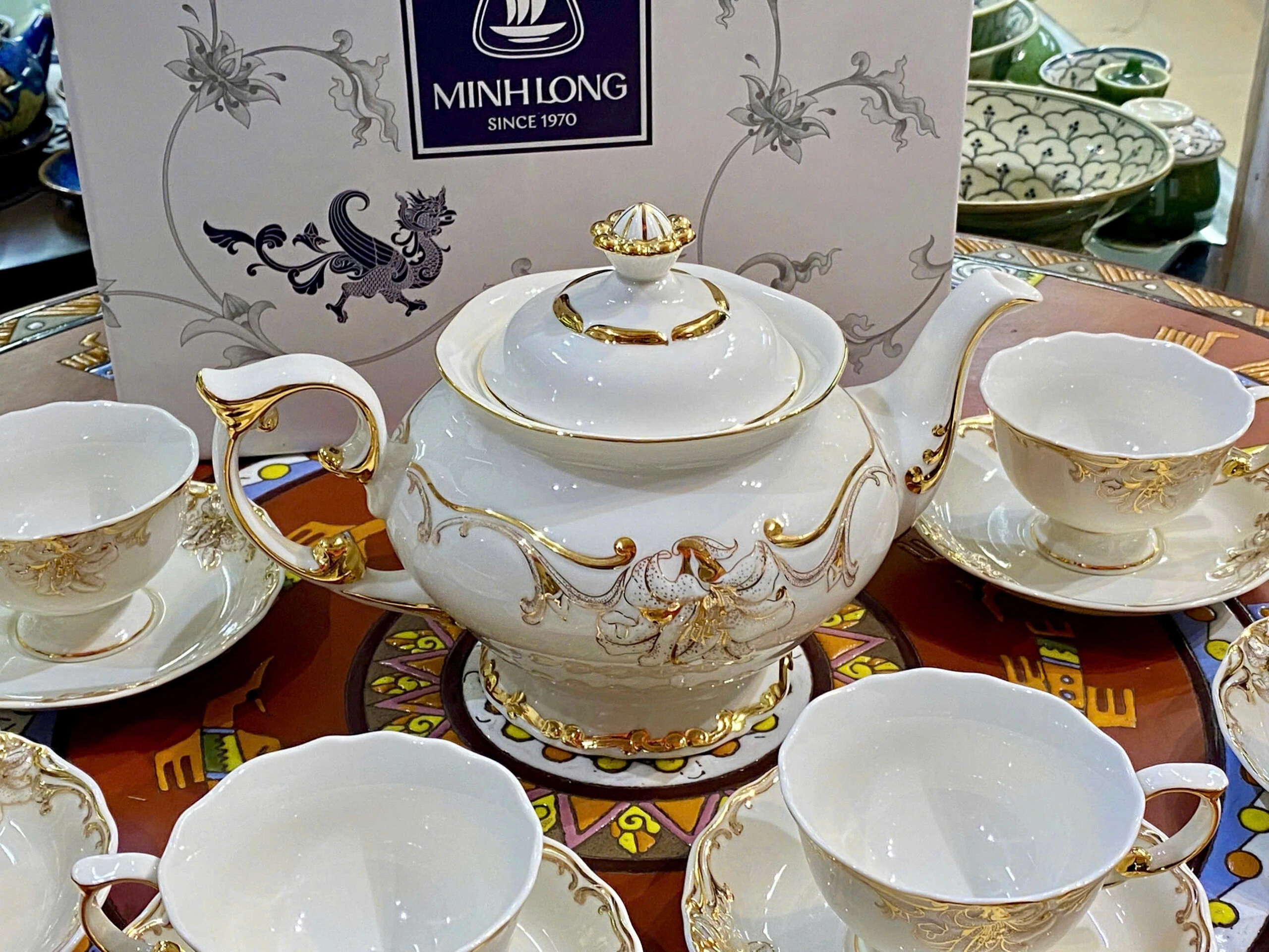 Ảnh nguồn cận ấm Đài Các với quai uốn bên trái, vòi cong bên phải, núm nắp hình hoa và chân đế, giữ họa tiết màu vàng