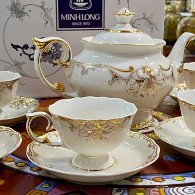 Ảnh nguồn cận chén Đài Các có chân, miệng lượn, quai uốn và đĩa hoa văn, giữ chữ MINHLONG SINCE 1970 trên hộp