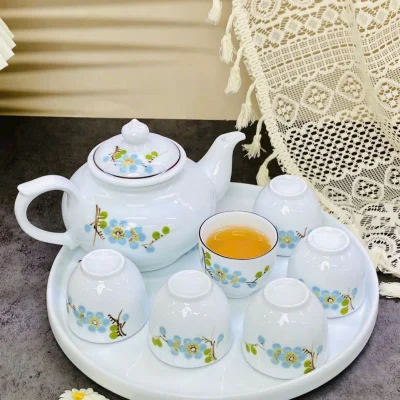 Ảnh chụp nguồn bản hoa màu xanh cùng dáng ấm, sáu chén không quai và khay tròn để so với bản hồng
