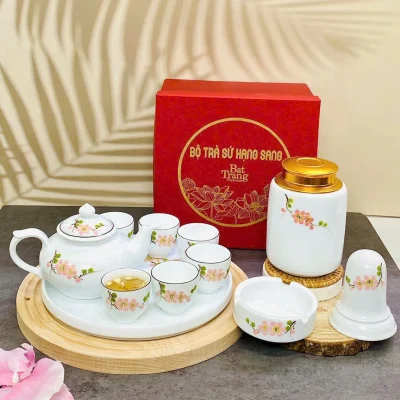 Ảnh nguồn phối bộ trà hoa màu hồng với lọ nắp màu vàng, các món phụ và hộp đỏ, giữ nguyên chữ trên hộp