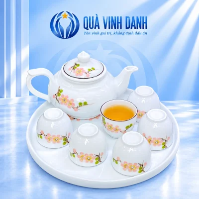 Bộ trà hoa màu hồng một ấm, sáu chén không quai và khay sứ tròn trên nền Quà Vinh Danh không bục