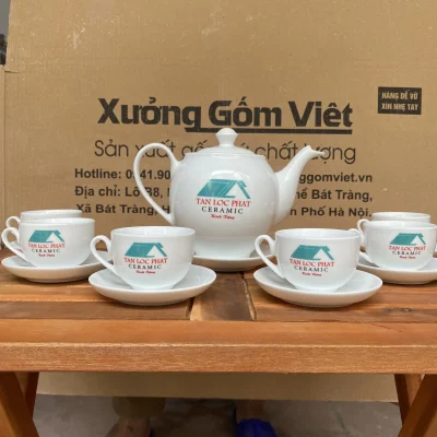 Ảnh thật nguồn bộ trà trắng in biểu trưng xanh TAN LOC PHAT CERAMIC Kính Tặng trên ấm và chén, giữ toàn khung bàn chụp