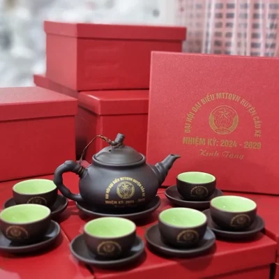 Ảnh chụp nguồn toàn bộ mẫu 14 lòng xanh với một ấm, sáu chén và hộp đỏ, giữ MTTQVN Huyện Cầu Kè nhiệm kỳ 2024–2029 Kính Tặng