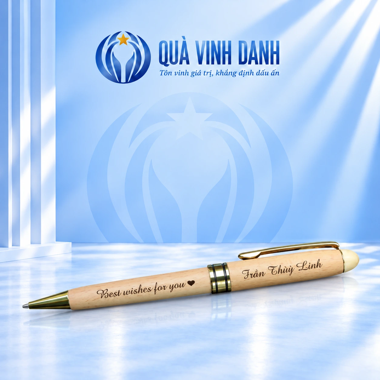 Bút gỗ sáng BGV 001 với đầu và cài màu vàng, giữ lời chúc cùng tên Trần Thùy Linh trên nền Quà Vinh Danh