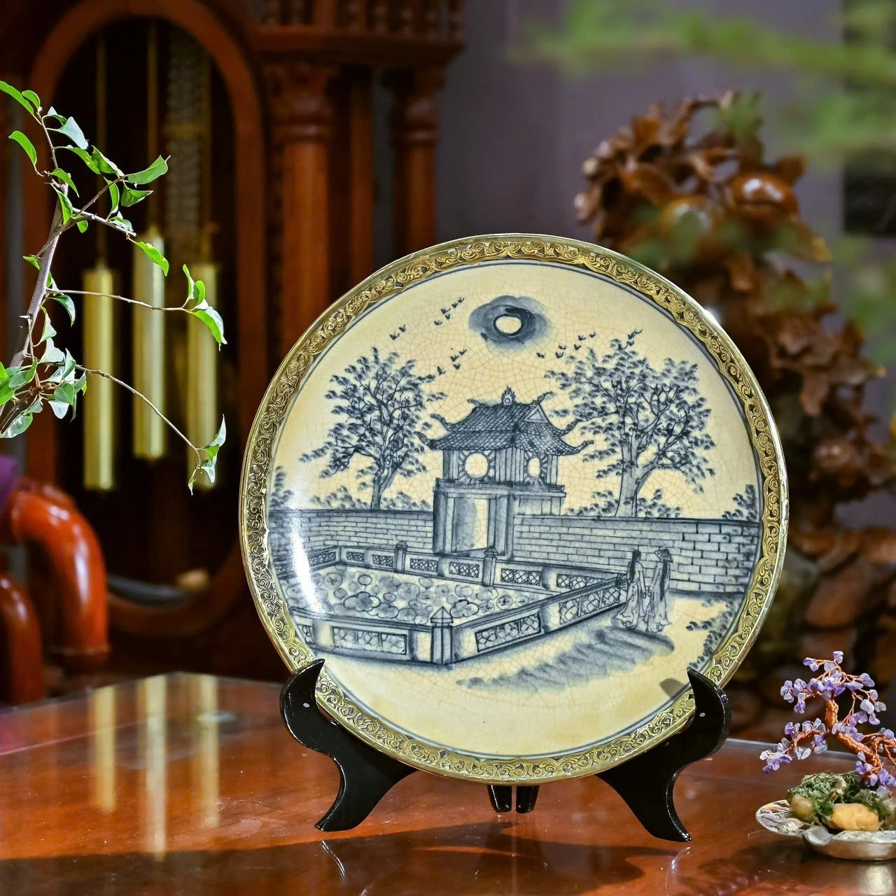 Ảnh chụp nguồn đĩa bọc đồng có cảnh lầu các, cây và mặt nước với viền hoa văn màu vàng
