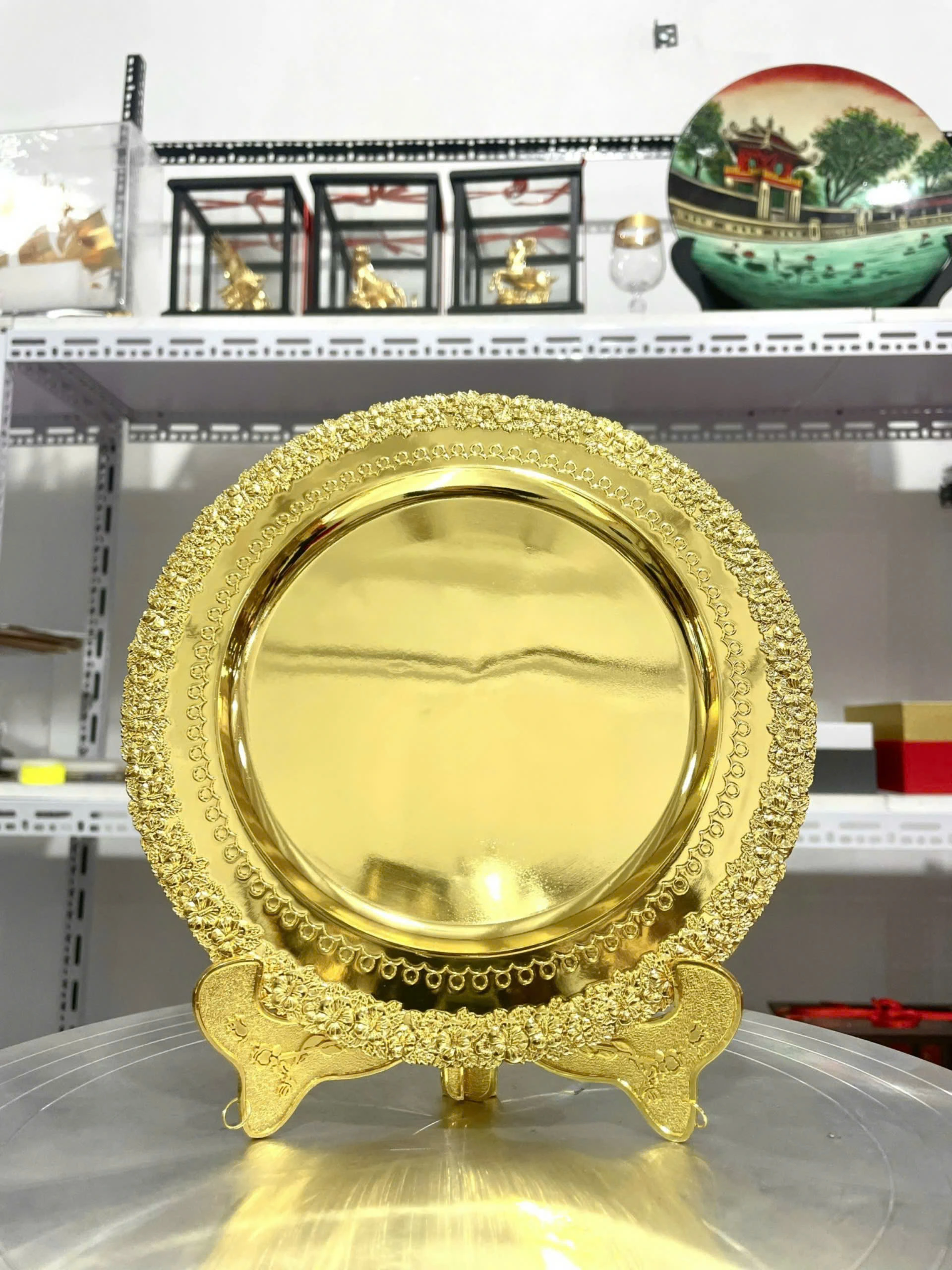 Ảnh thật bản trống đĩa kim loại mạ vàng viền hoa nổi trên giá đỡ màu vàng, khác kiểu giá đỡ của ảnh có chữ