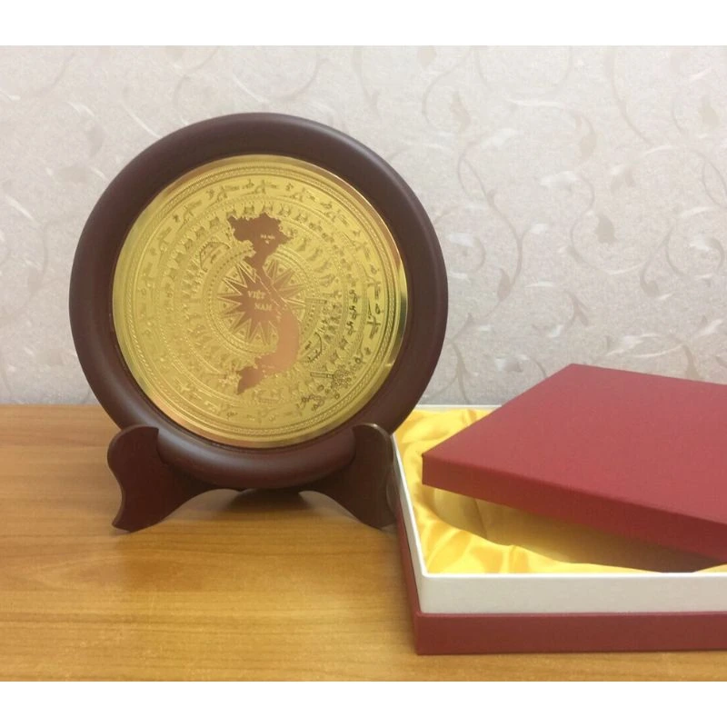 Ảnh chụp nguồn đĩa mặt hoa văn trống đồng và hình bản đồ Việt Nam, đặt cạnh hộp đỏ lót vàng