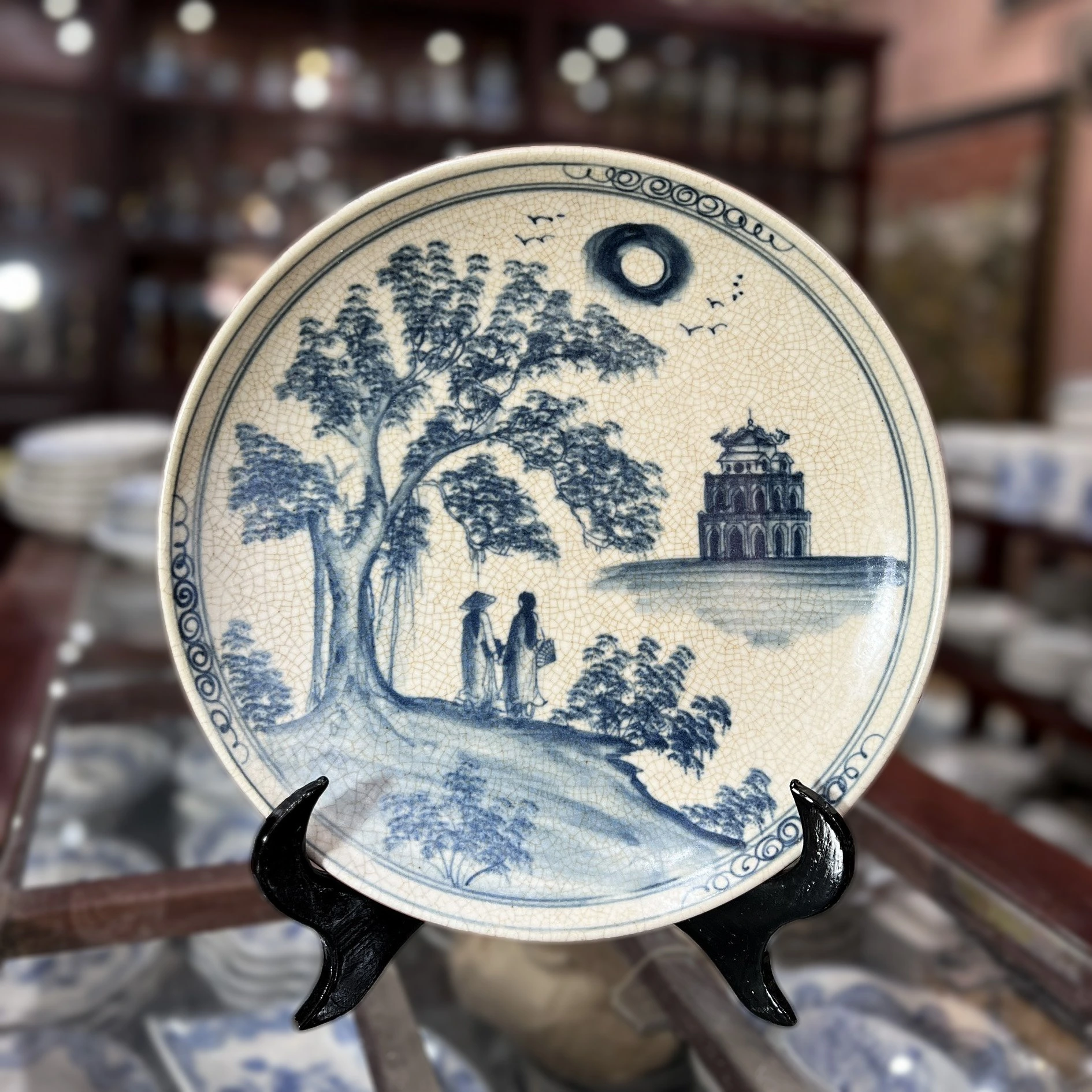 Ảnh thật đĩa men rạn có cây, cảnh tháp bên hồ và hình hai người, khác các mặt tranh khác trong bộ nguồn
