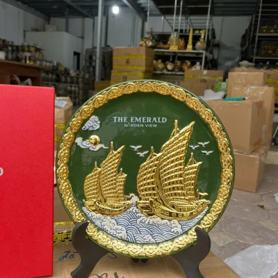 Ảnh chụp gần nguồn giữ nguyên hai thuyền màu vàng, sóng xanh trắng, viền nổi và hai dòng tên trên nền xanh