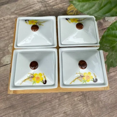 Bốn hộp đóng nắp hoa vàng, núm nâu xếp hai hàng trên khay gỗ trong ảnh nguồn