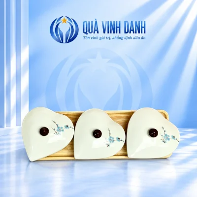 Ba hộp khay mứt dáng tim có nắp hoa xanh và núm nâu trên khay gỗ chữ nhật