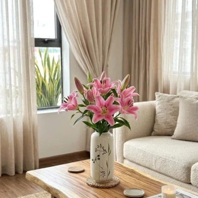Lọ hoa men trắng chuồn chuồn cắm hoa ly hồng trên bàn gỗ cạnh sofa sáng màu