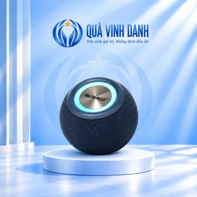 Ảnh đổi nền từ catalogue loa StarGO Boom Lite xanh dáng tròn bề mặt dạng lưới mặt bạc giữ logo hãng và vòng sáng xanh trên bục Quà Vinh Danh