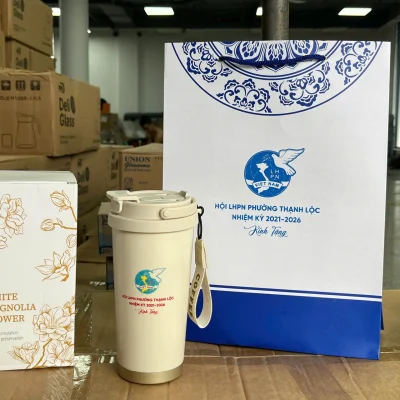 Ảnh thật nguồn ly Flower có chữ Hội LHPN Thạnh Lộc bên hộp hoa và túi in cùng nhiệm kỳ 2021–2026