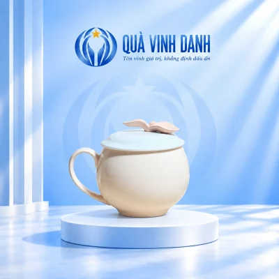 Ly sứ táo kem trơn, nắp xanh nhạt có núm hai lá trên bục nền xanh Quà Vinh Danh