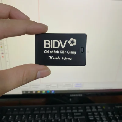 Ảnh thật nguồn chi tiết màu đen giữ BIDV Chi nhánh Kiên Giang Kính tặng, được cầm trước màn hình làm việc
