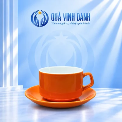 Minh họa một tách Capuchino màu cam lòng trắng, quai phải đặt trên đĩa cam trong nền Quà Vinh Danh không bục